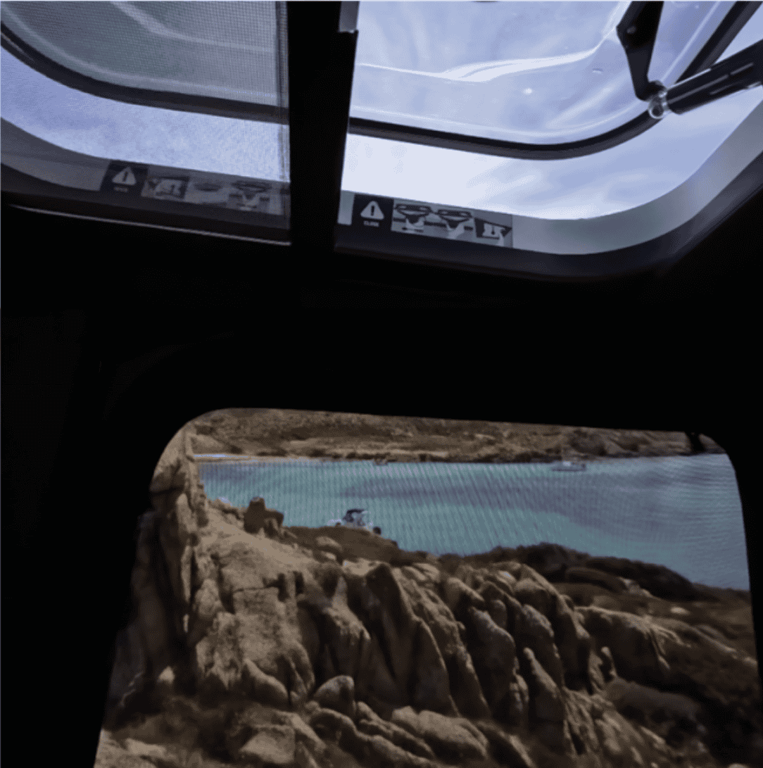 Vue intérieure de la tente de toit AirSky 360 Autohome avec ouverture panoramique sur paysage côtier